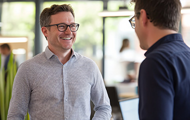 man smiling at another man in an office setting